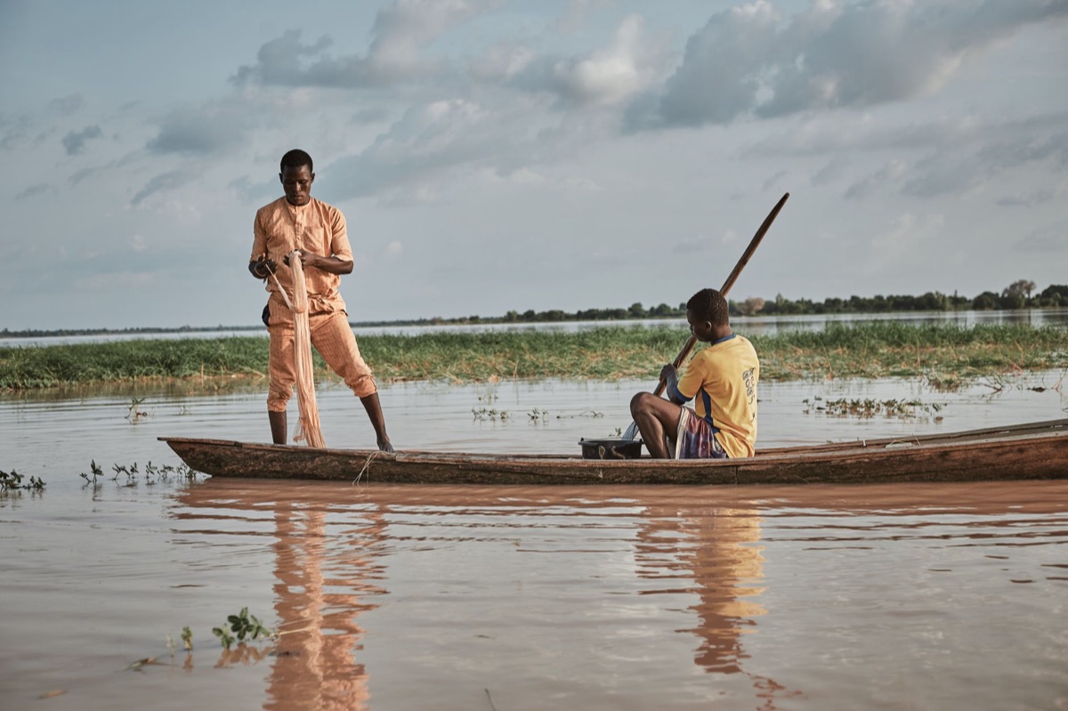 Pescador local em ação na praia de Miyako, com redes e peixes ao lado.